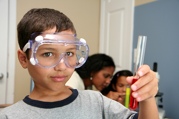 A girl with curly hair looks into a microscope