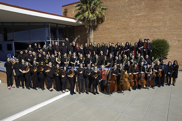 A group of music teachers stand outside a high school