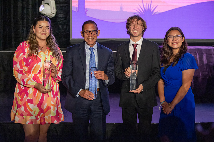 A woman, a man, a teen boy, and a woman smile on stage during the awards ceremony