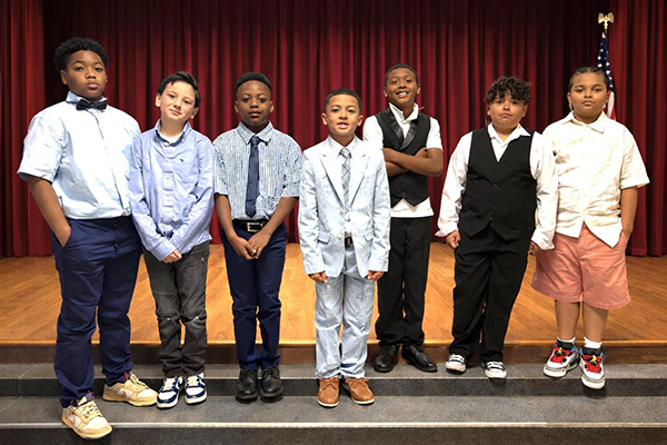 A group of boys wearing nice clothes standing on stage