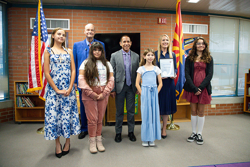 Four girls, two men and a woman smile for a group photo