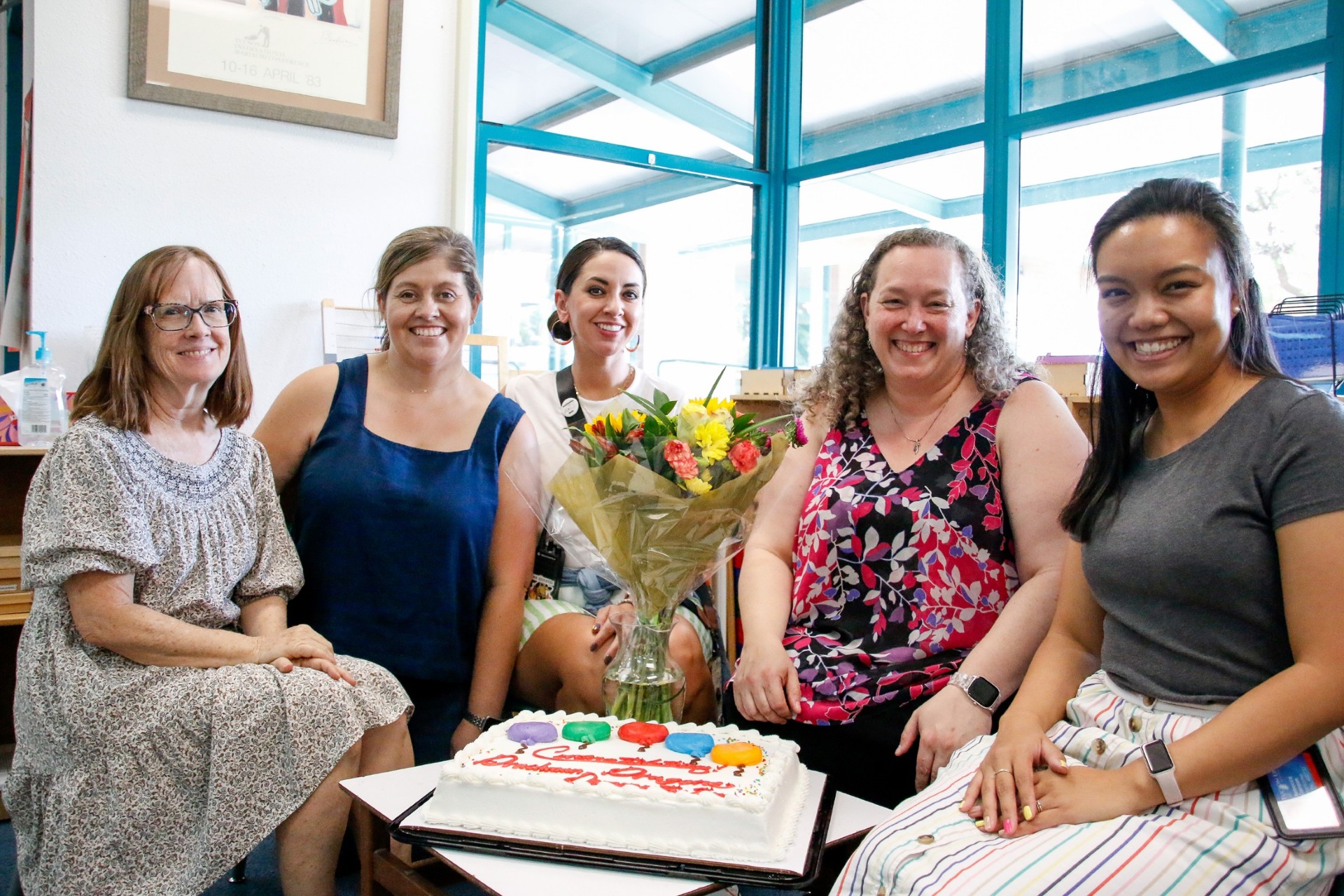 Drachman magnet staff smile with their celebratory flowers and cake