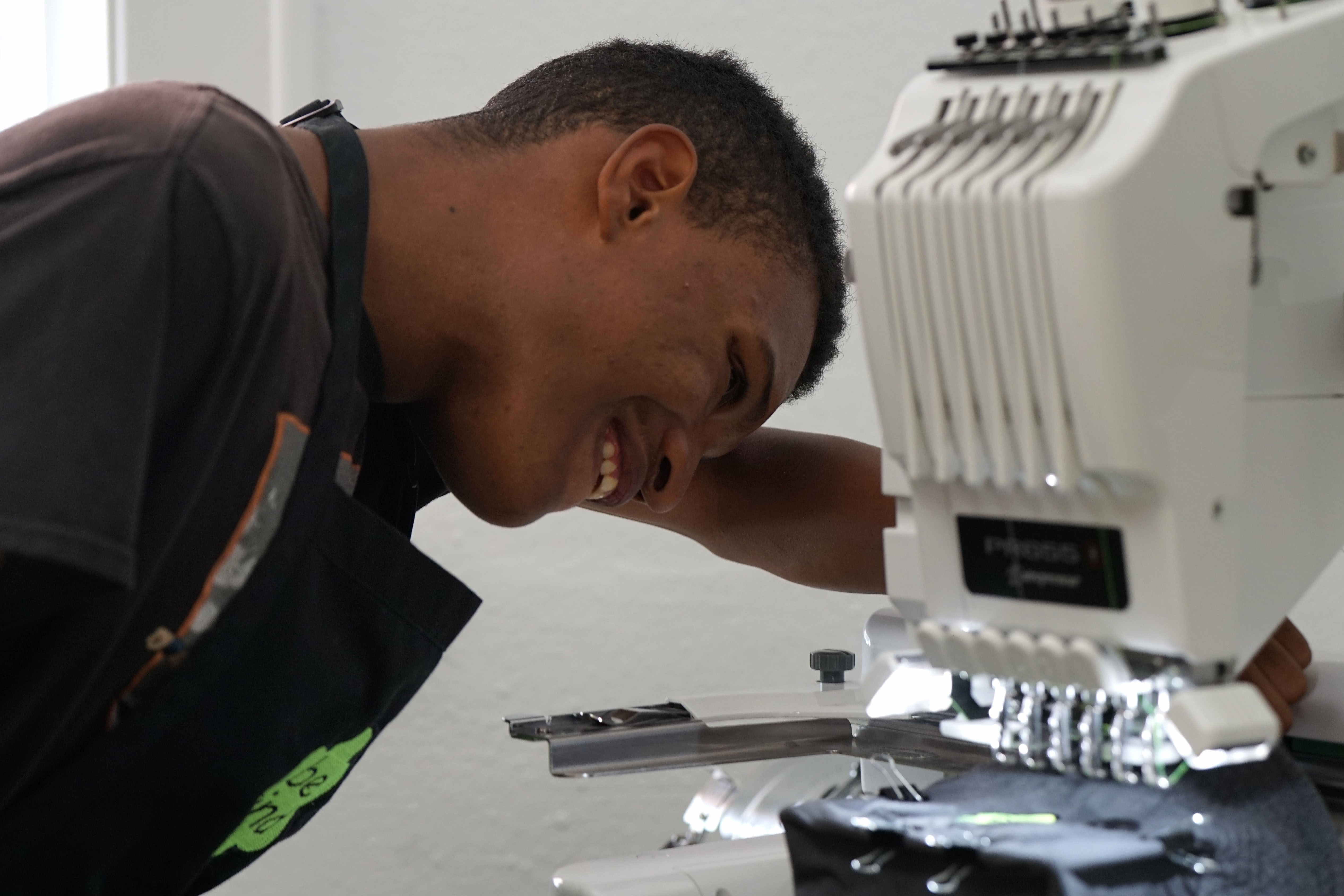 A student smiles as he works with a sewing machine