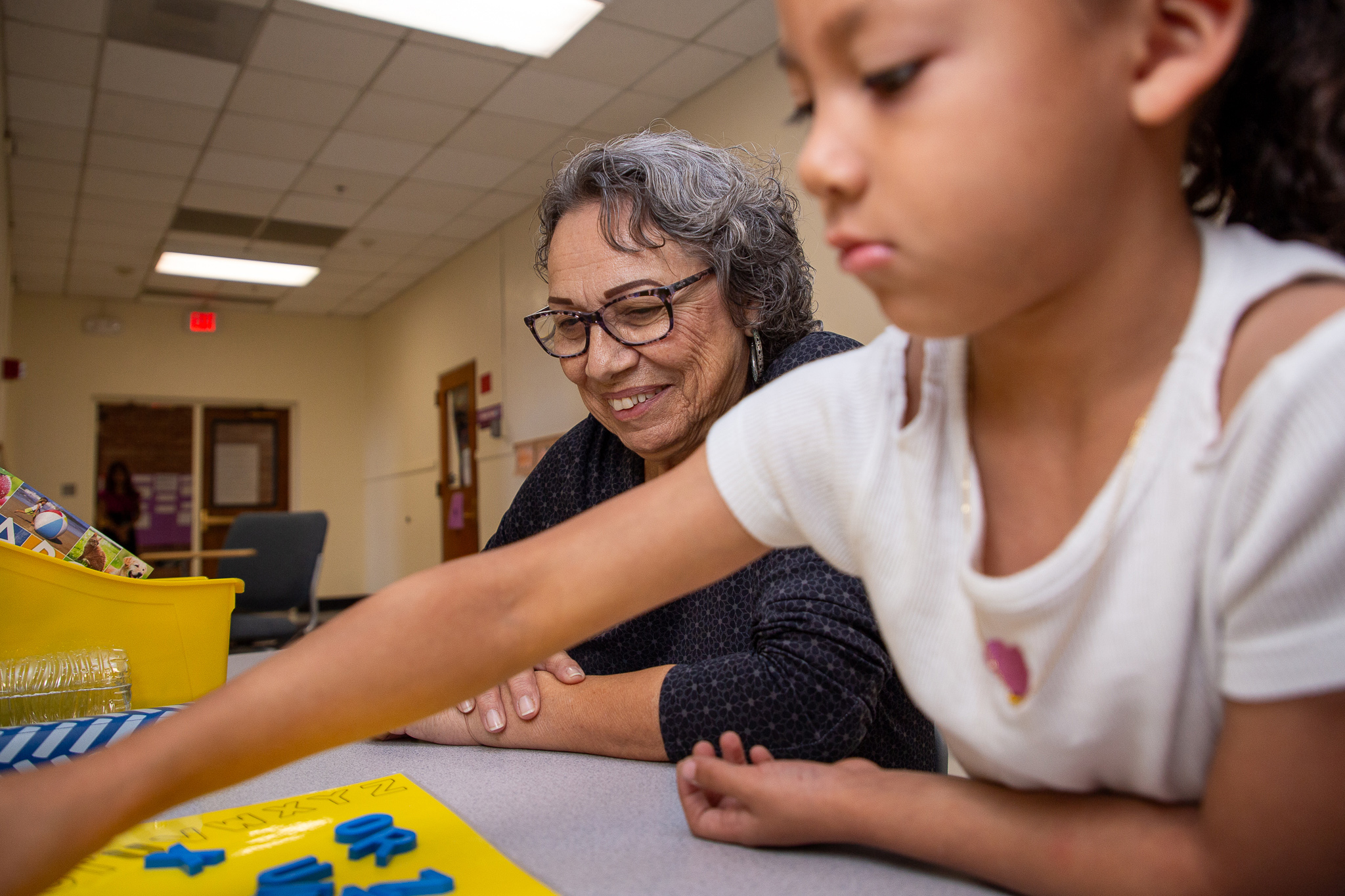 An older woman works with a young girl on putting together a puzzle