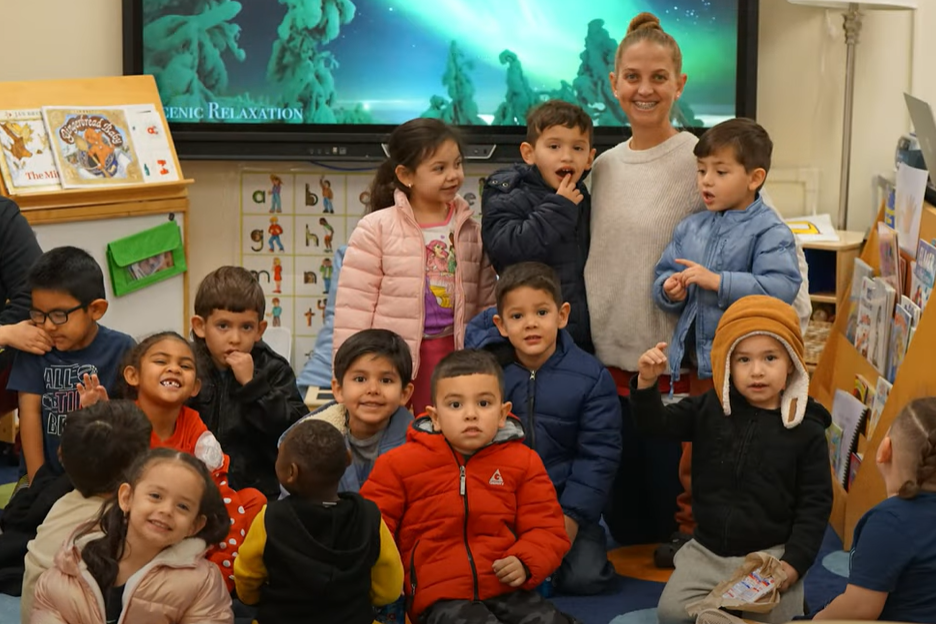 A teacher smiles with her preschool students