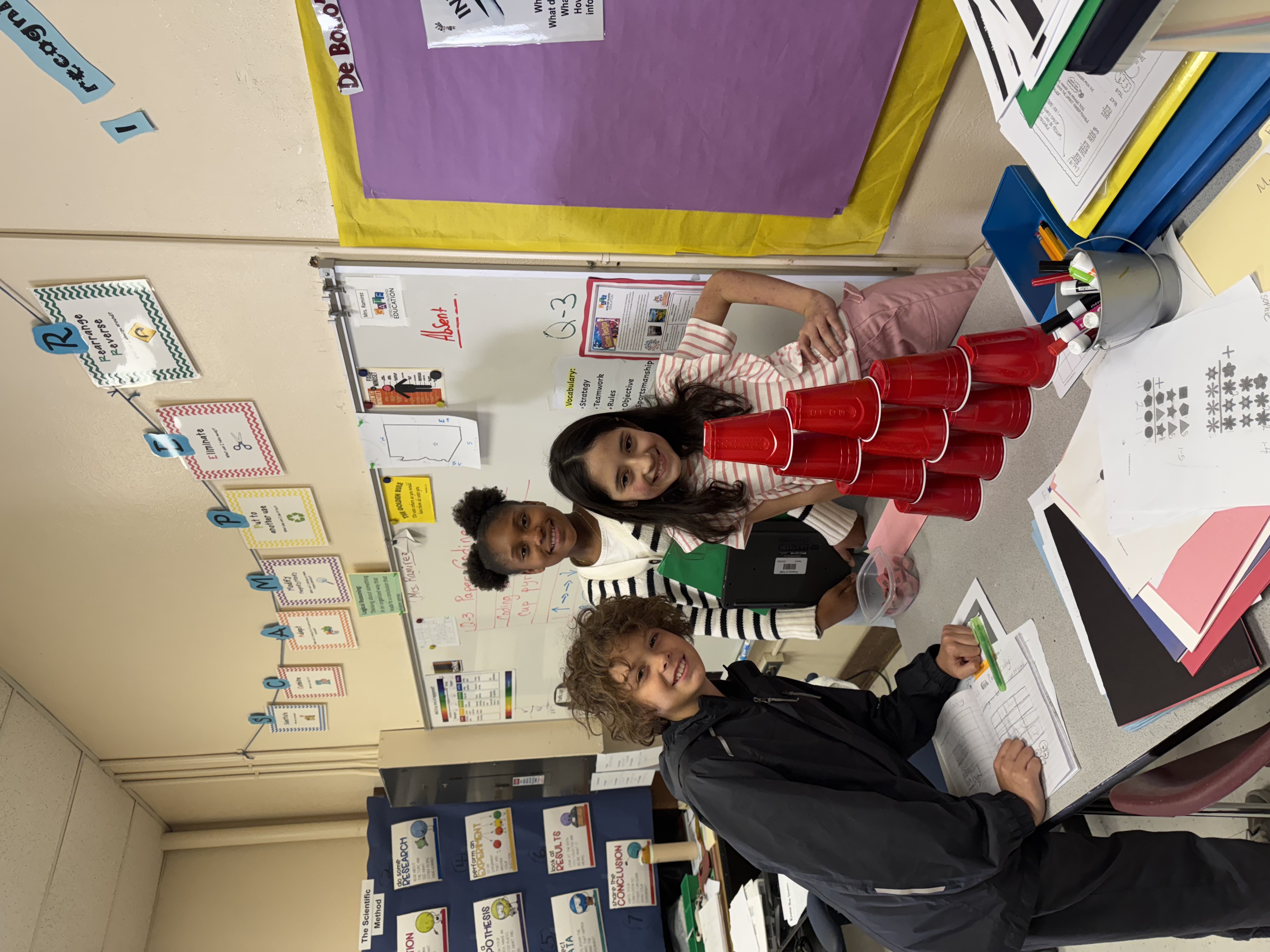 Student participating in a challenge involving stacking cups 4 then 3, then 2, then 1.