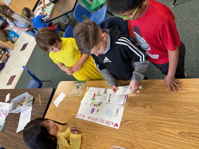 This image shows a student or students creating a board game as part of  the GATE program's GAME Design Unit.