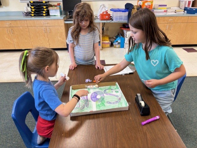 This image shows a student or students creating a board game as part of  the GATE program's GAME Design Unit.