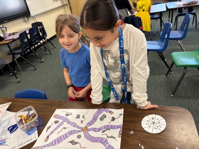 This image shows a student or students creating a board game as part of  the GATE program's GAME Design Unit.