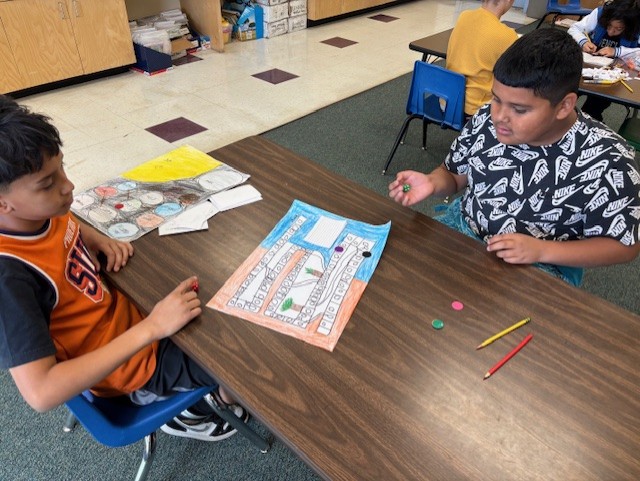 This image shows a student or students creating a board game as part of  the GATE program's GAME Design Unit.