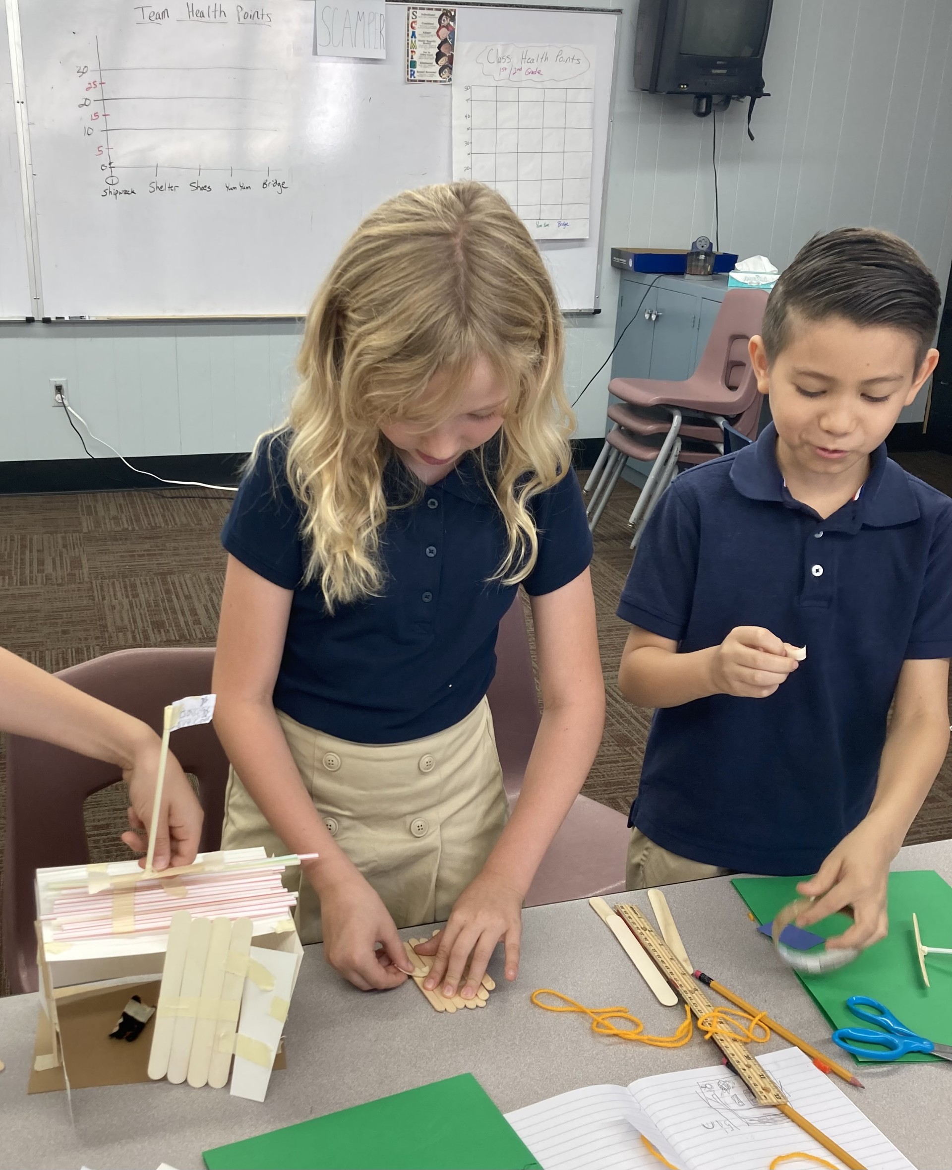 Picture features two of Mrs. Gallus's students making a shelter for the Survivor unit. 