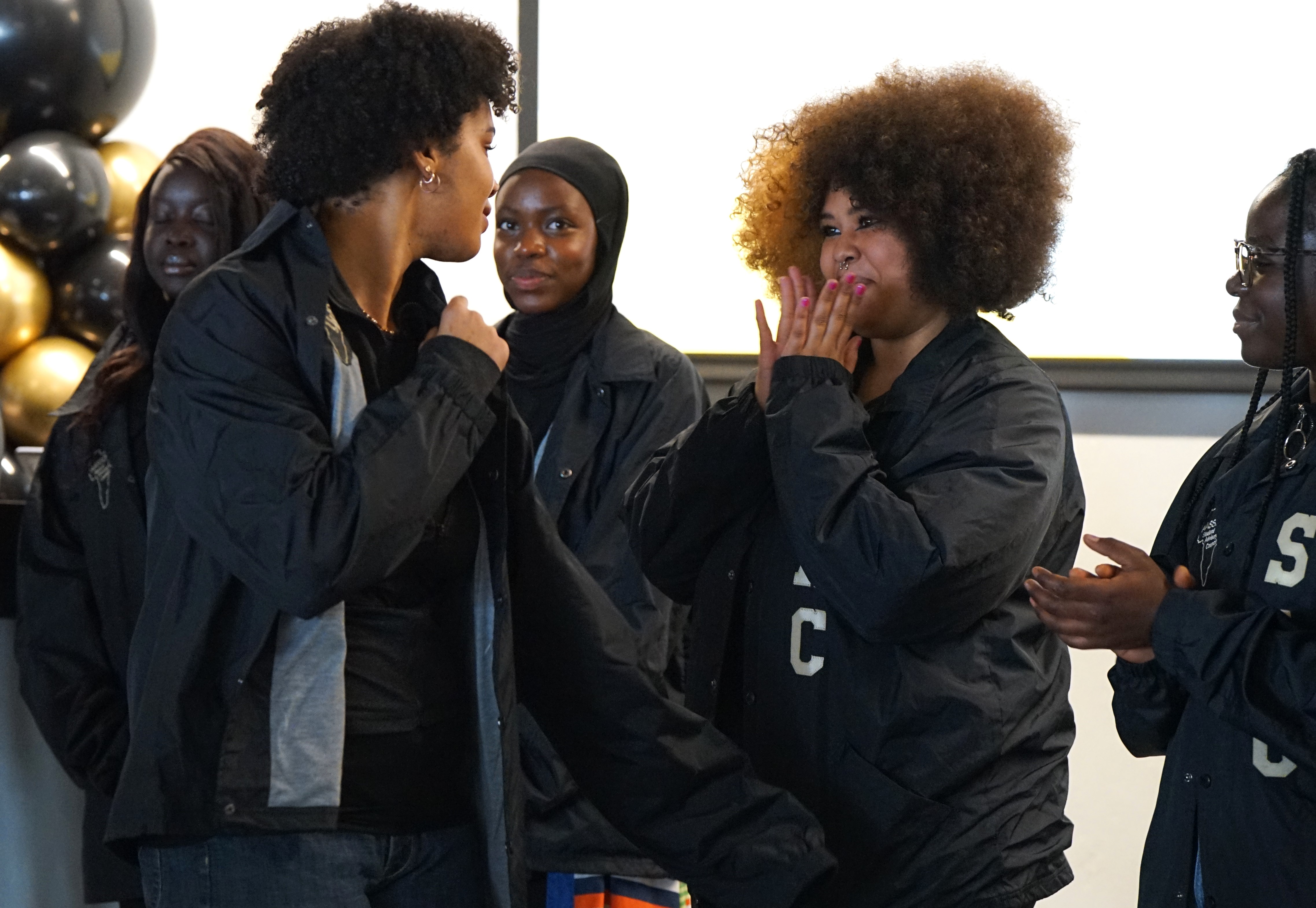 A student smiles at a woman after getting his new jacket