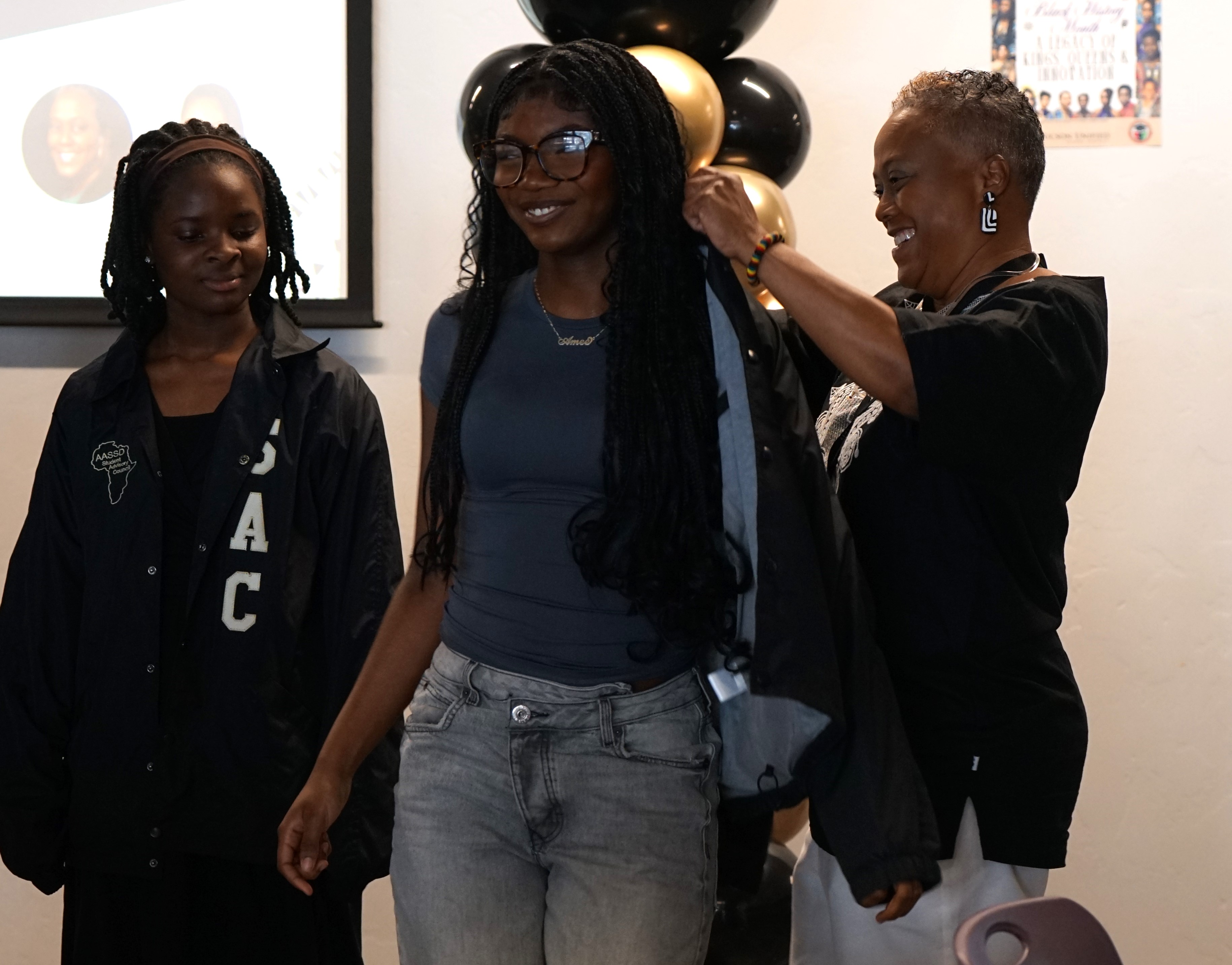 A girl in glasses smiles as she gets her jacket during the coating ceremony