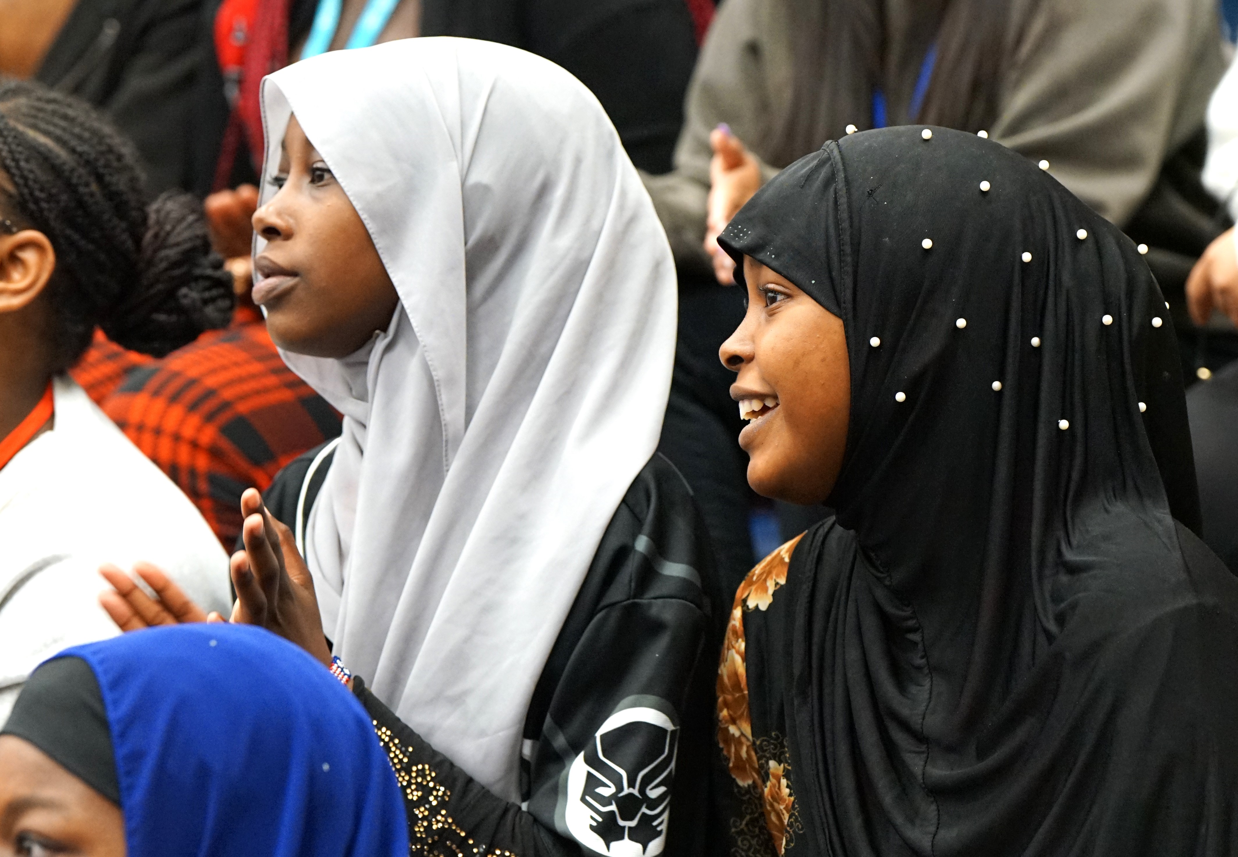 Two teen girls in headscarves clap