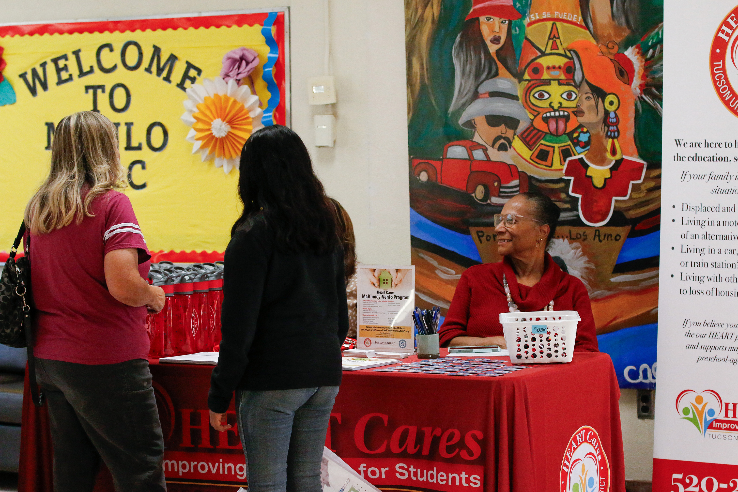 Two women browse freebies at a table for HEART Cares