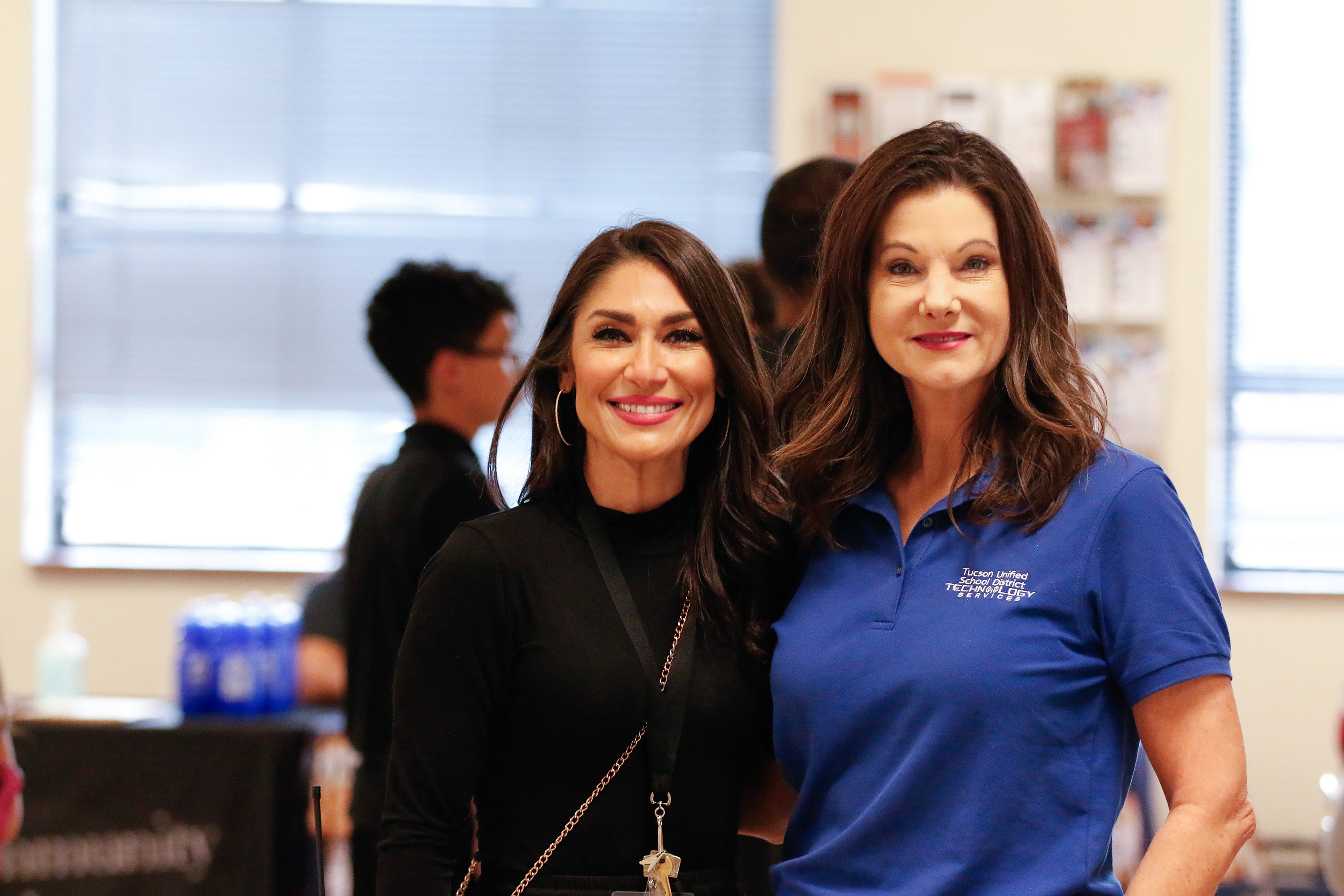 A woman in black smiles next to a woman in blue