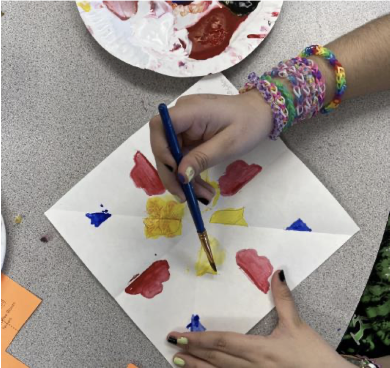 A woman paints a paper floral tile