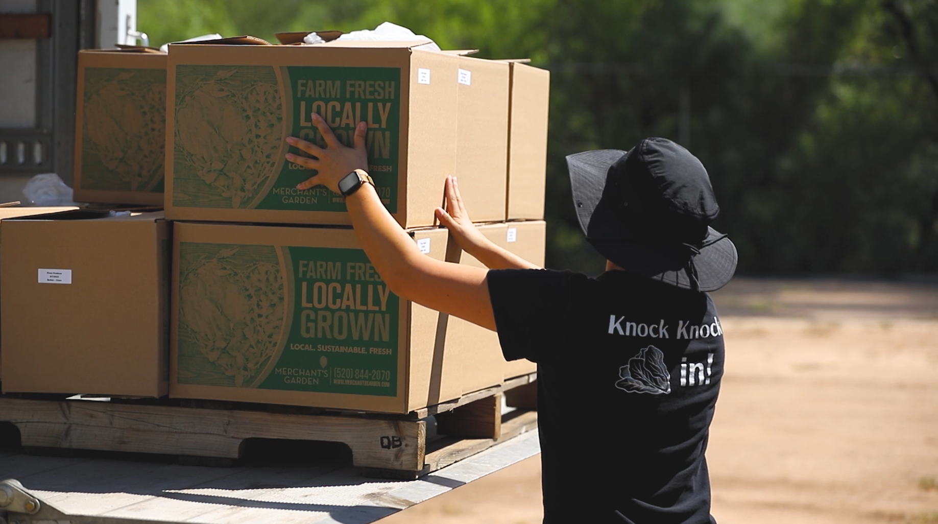 A Food Services worker loads boxed of fresh produce onto a truck