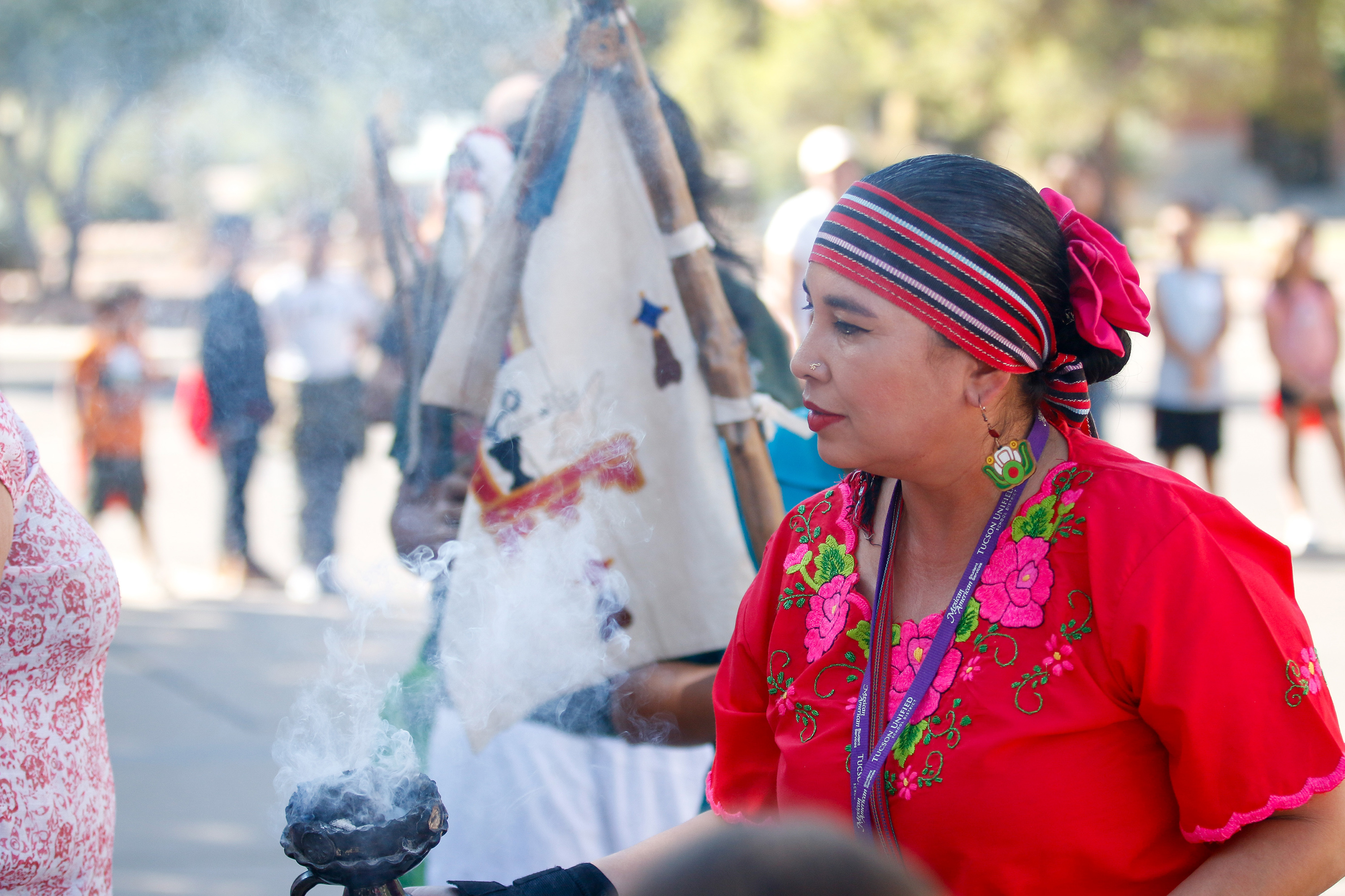 A woman in traditional Mexican dress performs a smudging ceremony