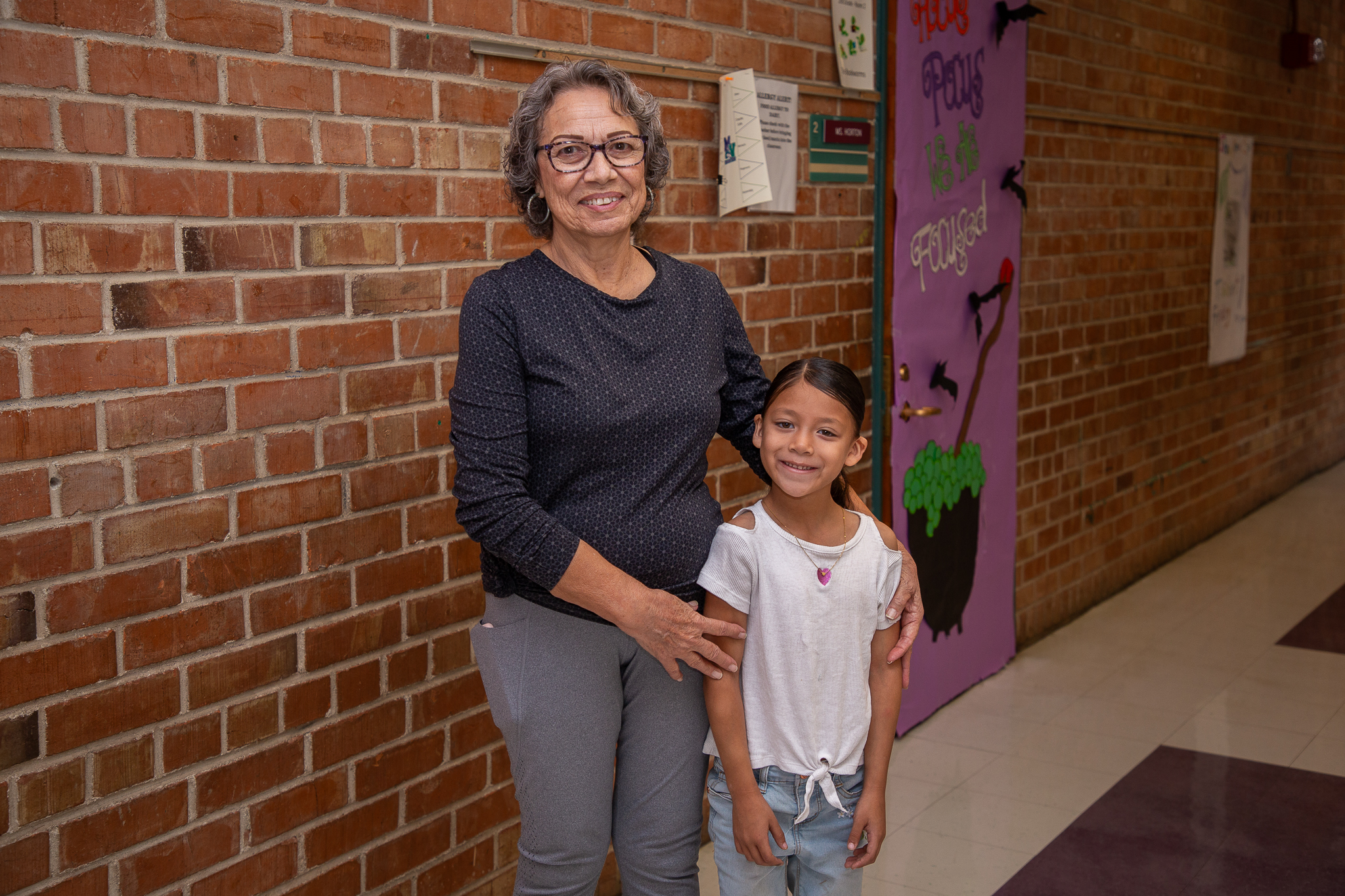 Dora Valentin and a young girl smile in the hallway of Mission View