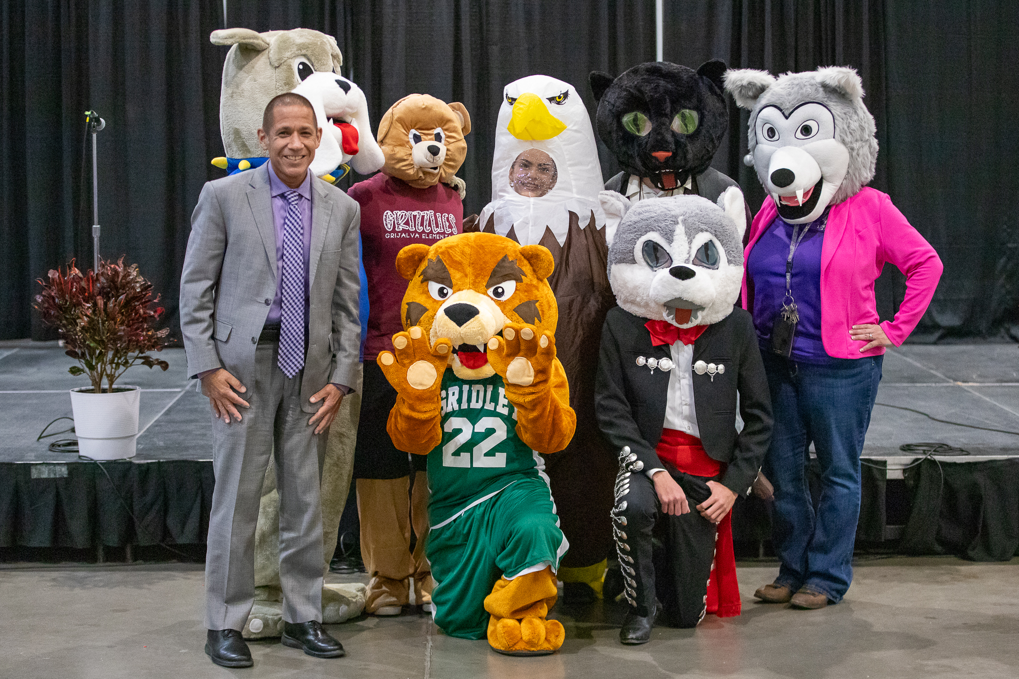 Dr. Trujillo smiles with several school mascots