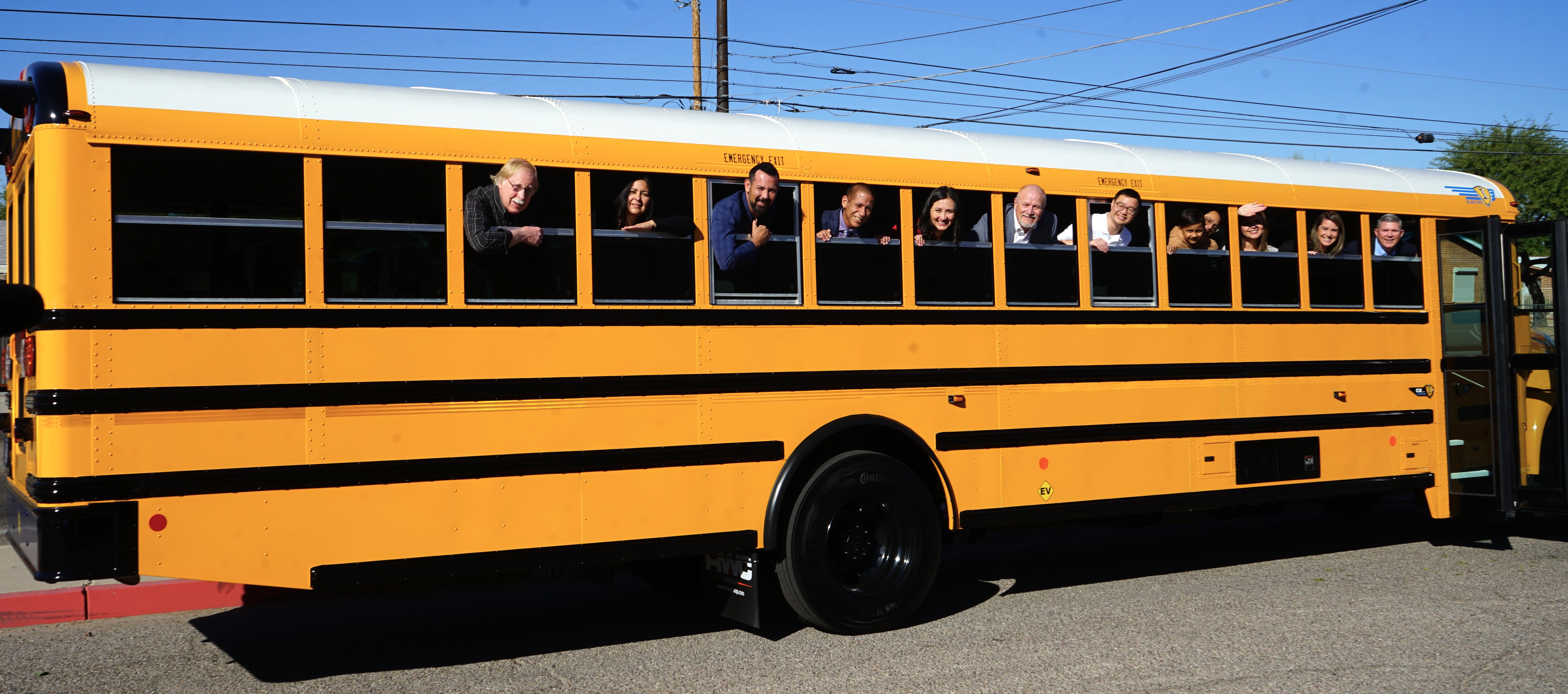 TUSD staff smile from the windows of an EV bus